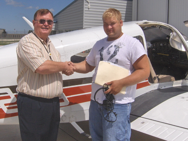 Picture of airplane owner Dave Pearson and Brad standing beside the Piper Warrior II used for training.